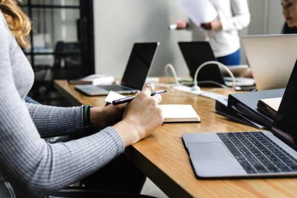 Um homem escrevendo em um laptop em cima de uma mesa.